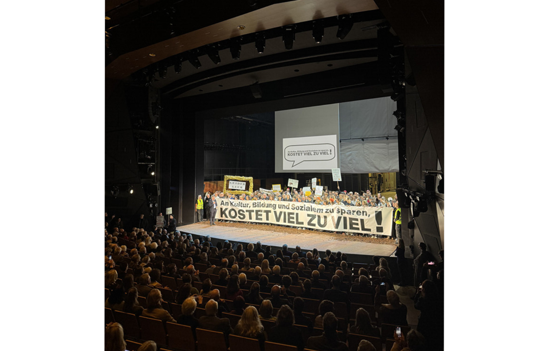 Protestaktion mit großem Schriftzug gegen Kürzungen.